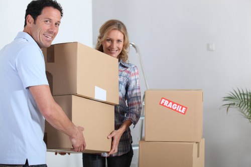 Professional movers carrying a sofa through a narrow Barnes staircase